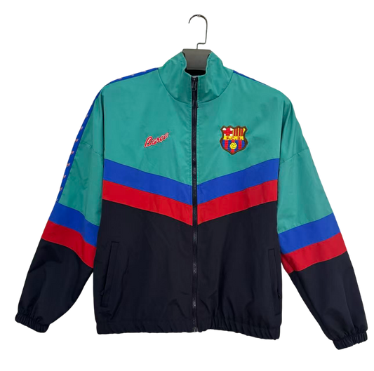 A vintage 1990s FC Barcelona track jacket by Lancer, featuring a teal upper chest and shoulders, a navy lower body and sleeves, and bold red and blue stripe accents across the chest and sleeves. The FC Barcelona crest is embroidered on the left chest, and the Lancer brand name is embroidered in red on the right chest.